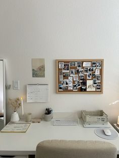 a white desk with a computer and pictures on the wall above it, along with a chair