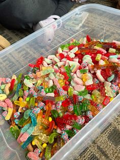 a plastic container filled with lots of gummy bears and other candies on top of a table