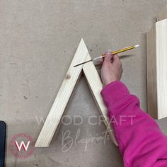 a person is making a triangle out of wood and glues it with a pencil