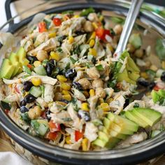 a salad with chicken, black olives, corn and avocado in a glass bowl