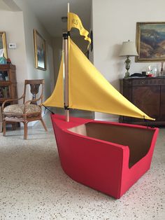 a red and yellow boat is sitting in the middle of a living room with chairs