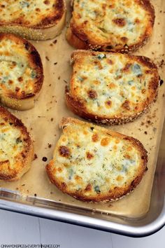 several pieces of bread with cheese on top in a pan, ready to be baked