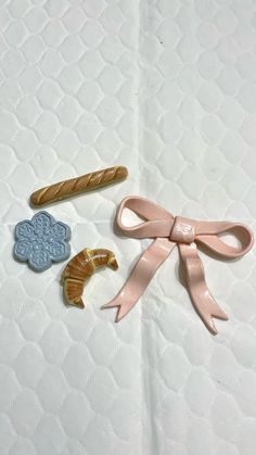 three different types of hair clips on a white sheet with pink ribbon and bowknots