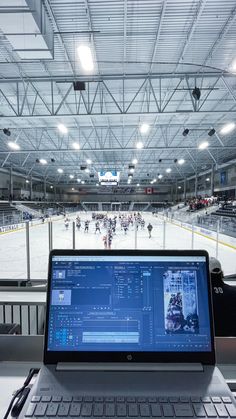 an open laptop computer sitting on top of a white table in front of a hockey rink