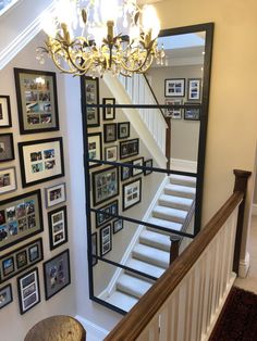 a staircase with pictures on the wall and a chandelier