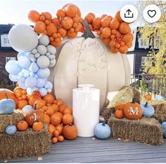 an arrangement of pumpkins, hay bales and balloons