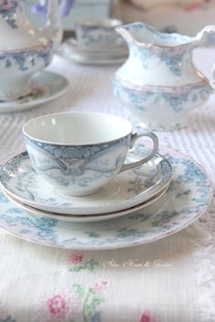 a white table topped with blue and pink china cups and saucers on top of each other