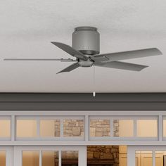 a ceiling fan mounted on the side of a wall in front of a door and windows