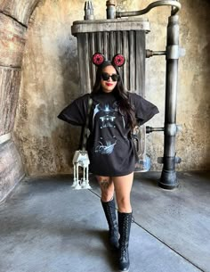 a woman wearing mickey mouse ears standing in front of an old fashioned steampunk machine