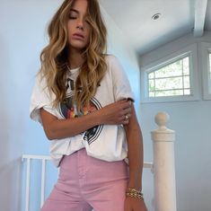 a woman in pink pants and a white t - shirt is posing for the camera