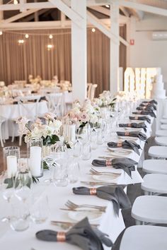 a long table is set with silverware and white linens for an elegant wedding reception