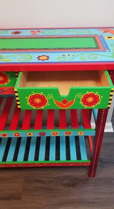 a colorful painted table with drawers on it