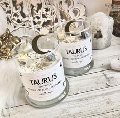 two glass candles sitting on top of a wooden table next to white and black decorations