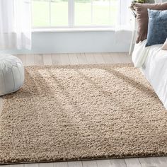 a bedroom scene with focus on the bed and rugs in front of the window