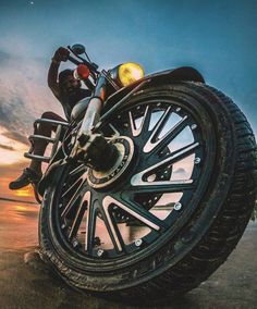 a man riding on the back of a motorcycle next to a beach at sunset or sunrise