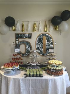 a table topped with lots of desserts and balloons in the shape of fifty five