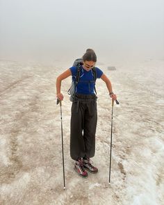 a man with skis and poles standing in the middle of an icy field on a foggy day