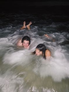 two people swimming in the ocean at night