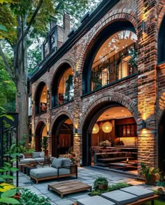 an outdoor living area with couches and tables in front of a large brick building