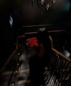 a woman sitting on top of a stair case next to a bunch of red flowers