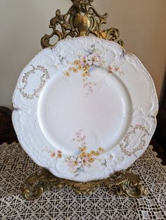 an ornate white and gold plate with flowers on it