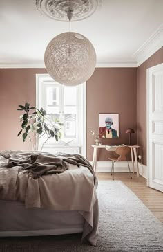 a bedroom with a bed, desk and plant in the corner on top of it