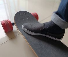 a person riding a skateboard on top of a hard surface floor with red wheels