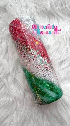 a red, green and white glitter tumbler on a furry surface