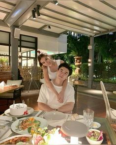 a man and woman sitting at a table covered in food