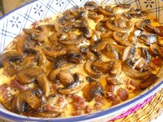 a casserole dish with mushrooms and ham on it in a blue and white bowl