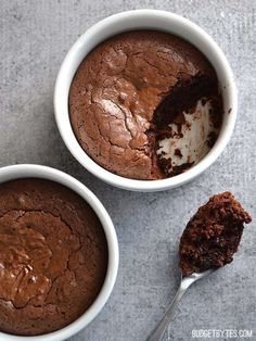 two white bowls filled with brownie and ice cream on top of a gray surface