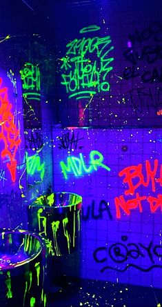 the bathroom is covered in neon graffiti and has blue walls with green, purple, and red writing on it