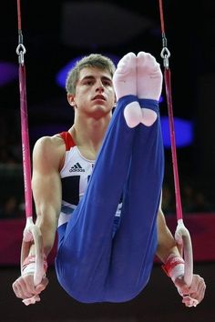 a young man is doing gymnastics on the rings