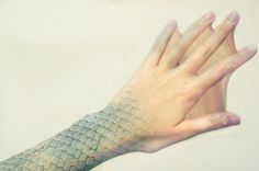 a woman's hand with a fish skin pattern on it, holding out her arm