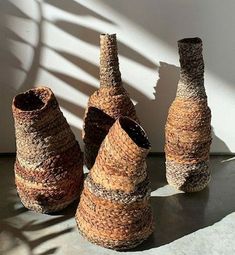 three woven vases sitting next to each other in front of a white wall and shadow on the floor