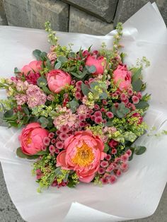 a bouquet of pink flowers sitting on top of a white wrapper next to a brick wall