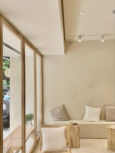 an empty room with two chairs and pillows on the floor next to large windows that look out onto a parking lot