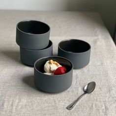 three bowls with ice cream and strawberries in them on a table next to a spoon