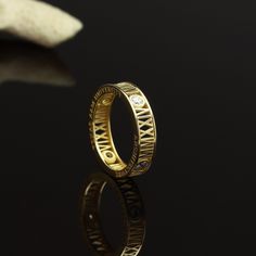 a gold wedding ring with roman numerals on the side and diamonds in the middle