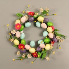 an easter wreath made out of fake eggs and flowers on a gray background with the words happy easter written below it