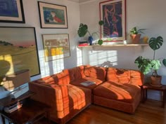 a living room with orange couches and pictures on the wall