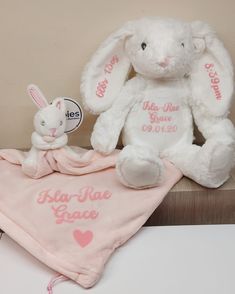 two stuffed animals sitting next to each other on top of a bed with pink blankets