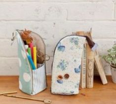 two pencils, pens and scissors are sitting on a table next to a white brick wall