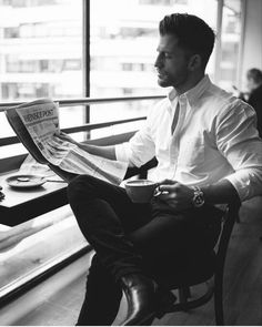 a man sitting in a chair reading a newspaper