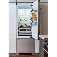 an open refrigerator with its door wide open and food in the bottom drawer is shown