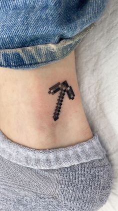 a small black and white tattoo on the ankle