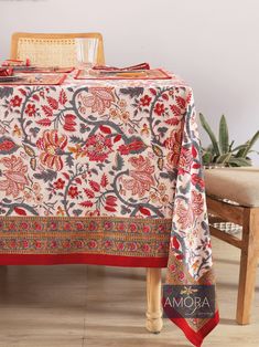 a table with a red and blue floral design on it, sitting next to a wooden chair