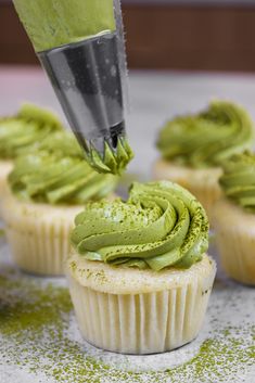 a cupcake being frosted with green icing