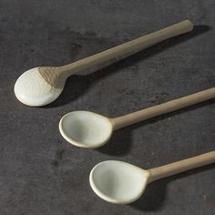 three wooden spoons sitting next to each other on a black counter top with one spoon in the middle