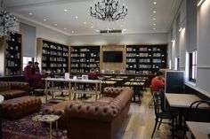 people are sitting at tables and chairs in a large room with many bookshelves